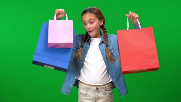 满意的少女提起购物袋 看着镜头笑着站在绿色屏幕的背景 白种人青少年自吹自擂购买彩色键的正面形象 — 图库视频影像