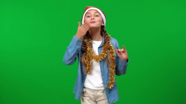 喜形于色的女孩头戴礼帽 举手投足 微笑着看着镜头挥动 在圣诞前夕 兴奋而快乐的白人青少年在绿色荧幕上摆出一副祝贺的模样 — 图库视频影像