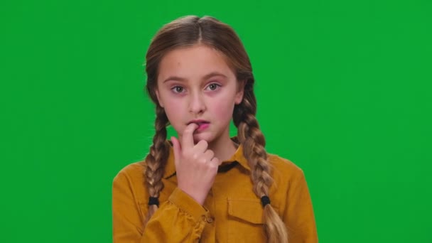 忧心忡忡的女孩咬着钉子 看着绿色屏幕上的摄像机 不确定的 踌躇的高加索少年对色彩关键背景思维的刻画 — 图库视频影像