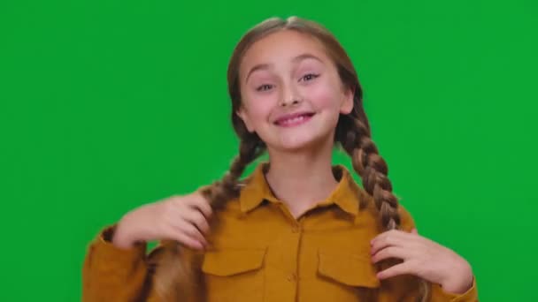 漂亮的女孩摸着辫子 微笑着在绿色屏幕上跳舞 看着相机 满足兴奋快乐的白人青少年在彩色背景上摆出玩乐姿势的特写 — 图库视频影像