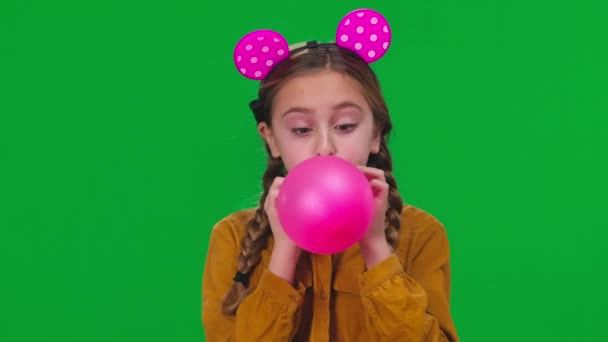 衣服少女吹粉色气球看着摄像头在绿色屏幕上 快乐的白人青少年在彩色背景特写处庆祝生日 — 图库视频影像