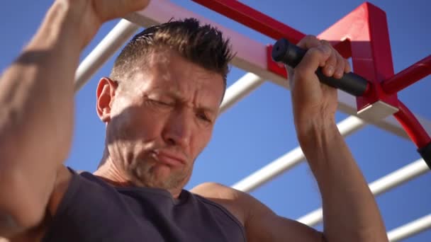 在阳光下锻炼的时候 集中精神的成年男子在横梁上吊着的特写手臂 夏季成年白种人户外运动训练 — 图库视频影像