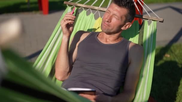 有思想的成年人躺在吊床上 躺在阳光下 用慢动作笔写日记 具有创造力的白人作家肖像画 在春夏的室外创作杰作 — 图库视频影像