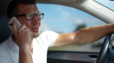 Telefonda konuşan sinirli bir adam gözlüğünü çıkartıyor. Stresli Kafkasyalı sürücünün portresi arabada oturmuş akıllı telefondan tartışıyor.