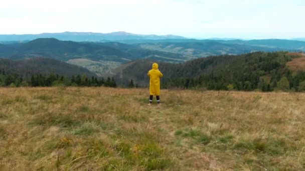 Achteraanzicht Man Gele Regenjas Staat Heuveltop Met Drone Passerende Toerist — Stockvideo