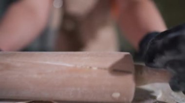 Lokanta mutfağında merdaneyle hamuru yuvarlıyoruz. Yakından tanınmayan beyaz kadın içeride hamur işi malzemesi hazırlıyor.