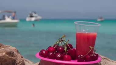Sahilde güneş ışığı altında meyveler ve meyve suyu ve ferahlatıcı içecek içen bir adamın ayrılışıyla. Kaygısız Kafkas erkek turist yaz tatillerinde mavi gölde güneşli bir günün tadını çıkarıyor.