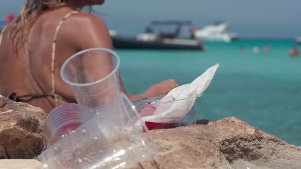 一个无法辨认的女人把塑料垃圾留在了海洋海岸 她在水里游向游艇 阳光明媚的日子里粗心的白人游客和室外有毒的污染垃圾 — 图库视频影像