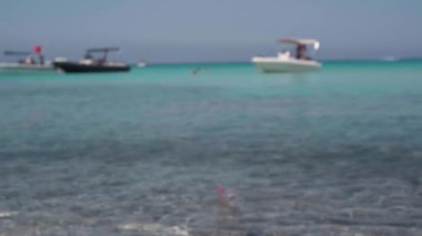 Tanınmayan bir kadın, cam gibi temiz suya plastik çöp atıyor Akdeniz deniz lagününden içeri giriyor. Beyaz kadın turist güneşli yaz gününde okyanusu kirletiyor.