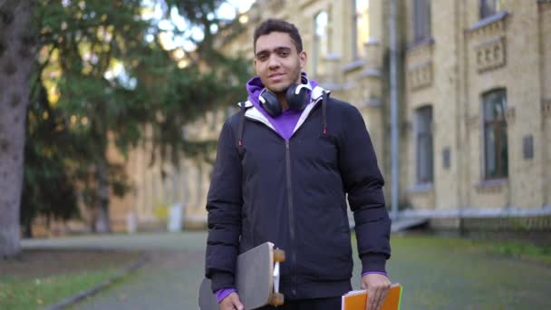 Молодой Уверенный Студент Университета Тетрадкой Скейтбордом Позирует Открытом Воздухе Разговаривая — стоковое видео
