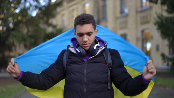 Joven Afroamericano Envuelto Bandera Ucraniana Pie Campus Mirando Cámara Sonriendo — Vídeos de Stock