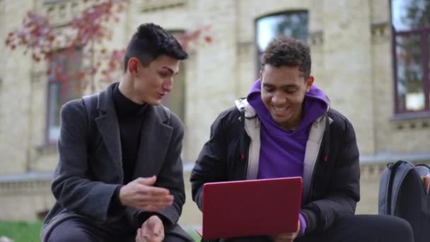 Dışarıda Dizüstü Bilgisayarla Oturmuş Gülümseyen Iki Pozitif Genç Adam Kafkas — Stok video