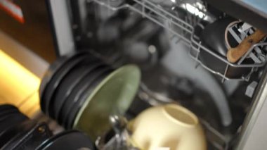 Kadın el, bulaşık makinesini açıp cam bardakları boşaltıyor. Evdeki mutfakta bulaşık yıkayan, tanınmayan, beyaz bir kadın.