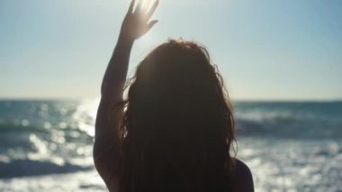 Günbatımında Akdeniz 'in arka planında güneş ışığında genç bir kadının arka plan silueti. Kafkasyalı turistin yavaş çekimde gün ışığına uzandığından emin.