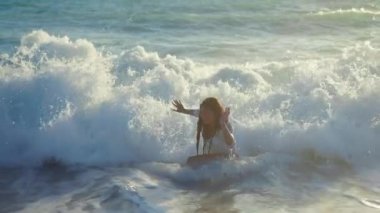 Kıbrıs 'ta Akdeniz' in köpüklü dalgalarında neşeli, heyecanlı genç bir kadın. Okyanus suyundaki neşeli beyaz turistin portresi güneş ışığında sahile vuruyor.