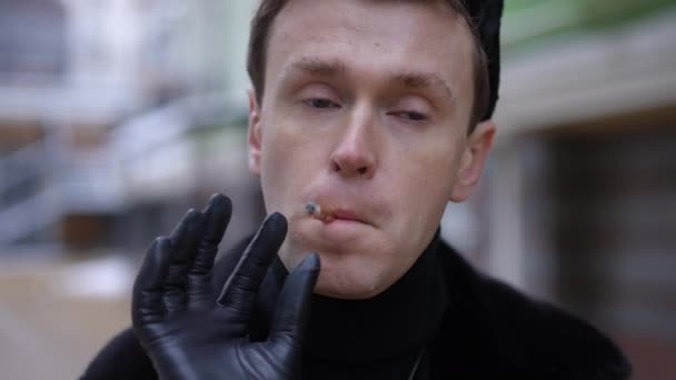 フロントビューを閉じる若いゲイの男性のカメラを離れてゆっくりと動きを見てタバコを投げ見て喫煙 都市部のLgbtの人のダウンタウンのクローズアップ肖像 — ストック動画