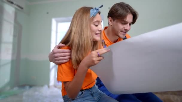 迷人的十几岁的女儿与年轻的父亲说话拥抱孩子 快乐的白人女孩与家长讨论家居装修设计蓝图 — 图库视频影像