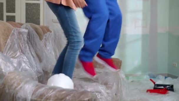 Ноги Радостного Мужчины Девушки Прыгающие Диване Покрытые Пленкой Сидящие Громко — стоковое видео