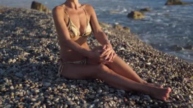 Zayıf, bronzlaşmış, tanınmamış bir kadın güneşli bir yaz gününde Akdeniz kıyısında güneşleniyor. Kafkasyalı turistin Kıbrıs 'ta tatilin keyfini çıkardığından emin