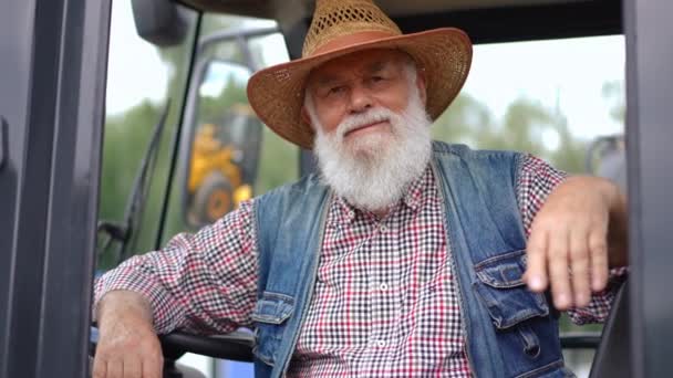 Седой Бородатый Белый Мужчина Смотрит Камеру Сидя Тракторе Улыбаясь Показывая — стоковое видео