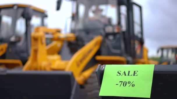 トラクターバケツの売り上げの7割が黄色い収穫機を背景に発表されました 屋外機械付きファーマーマーケットの黒い金曜日 — ストック動画