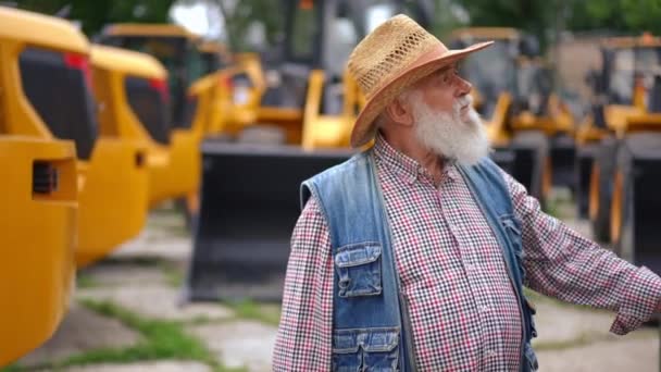 Бородатый Концентрированный Старший Человек Идет Наружному Рынку Сельхозтехники Выбирая Новый — стоковое видео