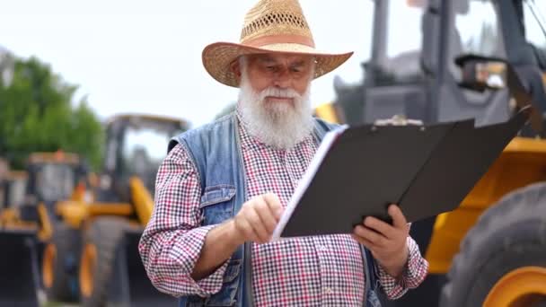 Retrato Anciano Barbudo Concentrado Examinando Documentos Aire Libre Con Tractores — Vídeos de Stock