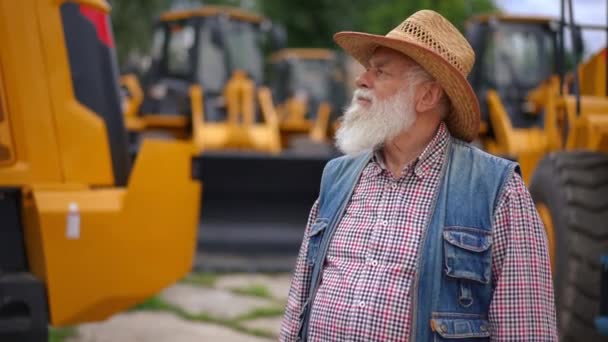 Senior Bebaarde Man Kijkt Rond Naar Nieuwe Tractoren Plukken Visitekaartje — Stockvideo