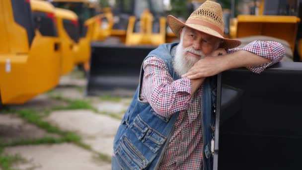 放大了快乐的老人的画像 他靠在拖拉机桶上 面带微笑地看着别处 满足白人农民在户外选择新车的现场摄像方法 — 图库视频影像