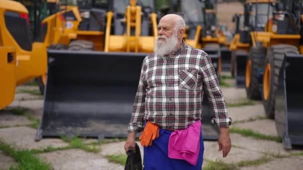 多利拍摄了自信的资深工程师的肖像 他环视着巨大的农业收获者 前景专业白种人在户外散步修理车辆 — 图库视频影像