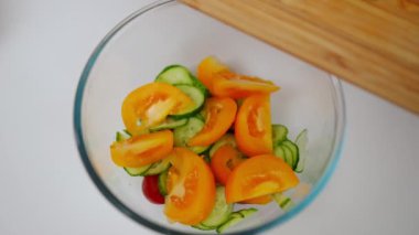 Sebzeli yakın plan salata kasesi ve tabağa dilimlenmiş yeşil soğan ekleyen tanınmayan bir kadın. Kafkas ev hanımı ağır çekimde lezzetli yemekler pişiriyor.