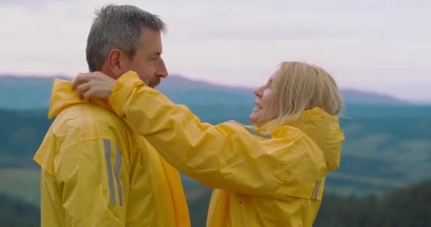 Usmívající Žena Obléká Kapuci Žlutého Pláště Muže Stojícího Vrcholku Hory — Stock video
