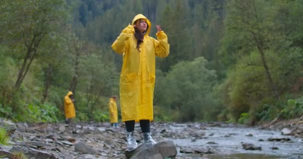 Weitschossene Unbeschwerte Junge Frau Gelbem Regenmantel Steht Auf Einem Stein — Stockvideo