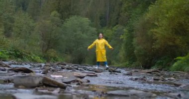 Geniş açılı beyaz kadın dağ nehrinde kollarını uzatıyor. Gülümseyen mutlu bayan turist tatillerde eğleniyor. Sinema 4k ProRes Merkezi