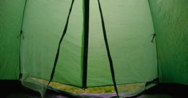 Kafkasyalı genç bir kadının fermuarını açtığı yeşil çadır. Dağlarda kamp yapmaktan hoşlanan sarı yağmurluklu kendine güvenen kadın turistin portresi. Sinema 4k ProRes Merkezi