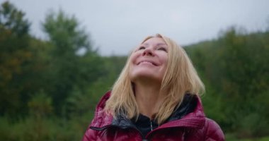 Mutlu, rahat bir kadının yakın plan portresi. Yaz günü dağ çayırında durup gülümseyen bir kadın. Kaygısız Kafkas kadın turist tatillerde eğleniyor. Sinema 4k ProRes Merkezi