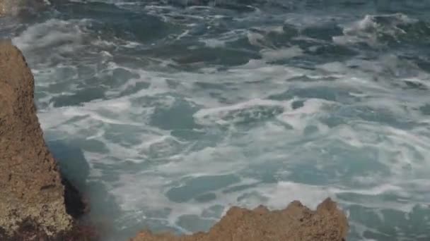 地中海的特写蓝色波浪 阳光下有白色泡沫 塞浦路斯沿海岩石上的水花洒在室外 — 图库视频影像