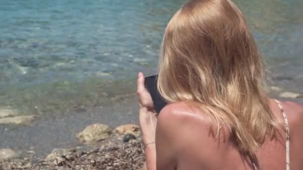 Donna Bionda Messaggistica Online App Smartphone Sulla Spiaggia Del Mediterraneo — Video Stock