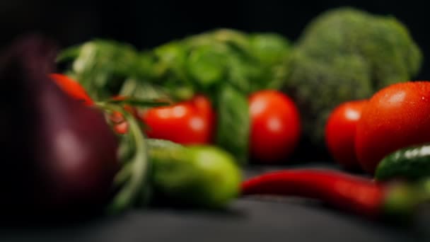 スローモーションで有機野菜とテーブルの上に転がりおいしい赤いトマト 黒を基調とした美味しい食材のクローズアップ — ストック動画