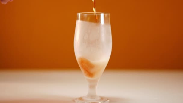 冷冰冰的特写镜头和慢镜头下倒入的啤酒 橙色背景的清爽饮料 — 图库视频影像