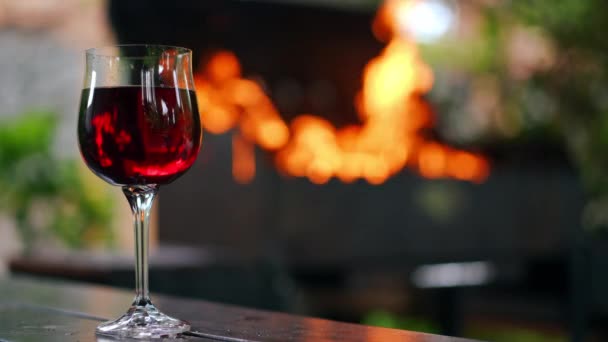 左手边有一小杯红葡萄酒 背景中燃烧着燃烧的火焰 倒映在饮料中 户外后院野餐 — 图库视频影像