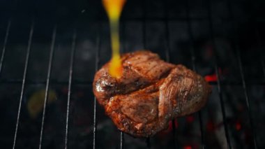 Yavaş çekimde ızgarada pişmiş bifteğe bbq sosu döküyorum. Manzaralı, yakın plan, lezzetli piknik yemekleri ızgaranın üstünde baharatlı.