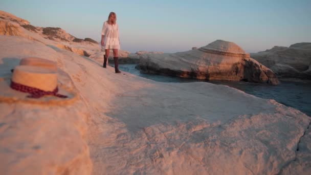 Mujer Caucásica Despreocupada Vestido Blanco Paseando Atardecer Dorado Sobre Rocas — Vídeo de stock