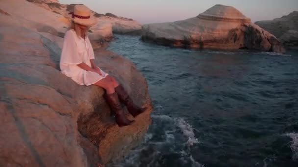 Szczupła Opalona Kobieta Białej Sukience Słomkowym Kapeluszu Siedząca Skale Morzu — Wideo stockowe