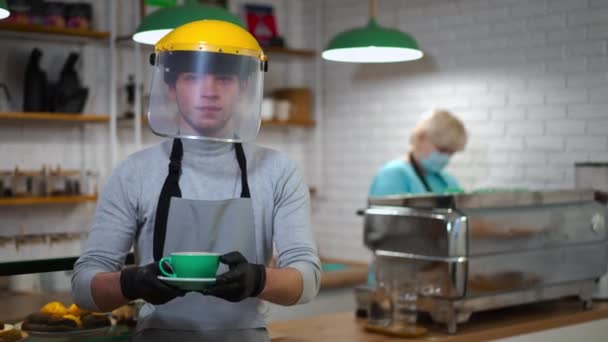 Hombre Joven Escudo Facial Estirando Taza Café Cámara Pie Izquierda — Vídeo de stock