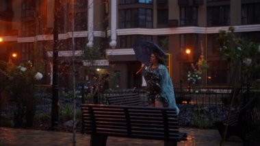 Canlı kamera, şemsiyeli, düşünceli, beyaz bir kadına yaklaşıyor. Gece caddesinde dikilip etrafa bakıyor. Şehir merkezindeki geniş ölçekli kadın portresini büyüt.