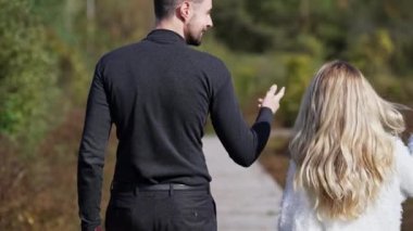 Güneşli bir günde gezen mutlu, beyaz bir çiftin arka plan görüntüsü. Canlı kamera pozitif erkek ve kadının yürüyüşünü takip ediyor.