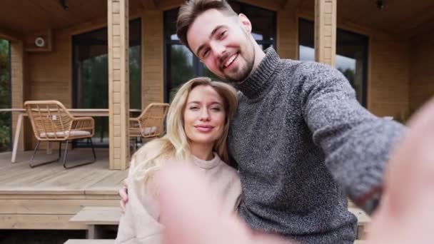 屋外の新しい夏の家の前で写真を撮る幸せな夫婦の自撮りハメ 白人大好き男と女見ますカメラポーズ撮影ビデオのためにソーシャルメディア — ストック動画