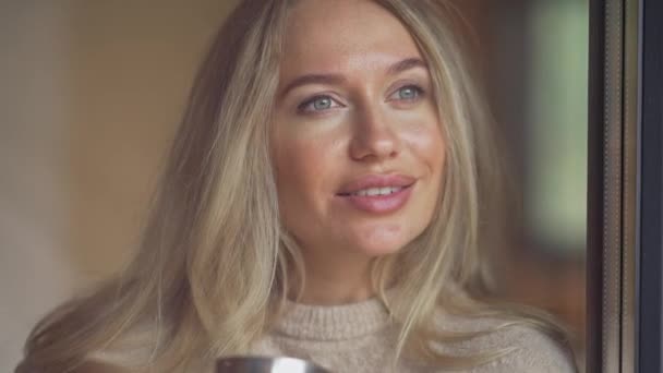 Portret Pięknej Blondynki Białej Kobiety Niebieskimi Oczami Uśmiechniętymi Przez Okno — Wideo stockowe