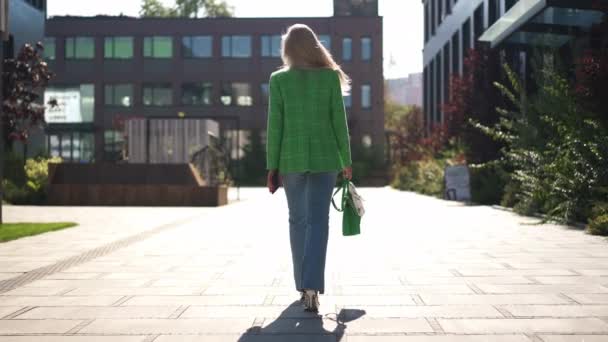 跟踪拍摄到一个自信的女商人在市中心阳光下慢行的照片 日出时分在城市街道上漫步的成功白人妇女的背景全景 — 图库视频影像